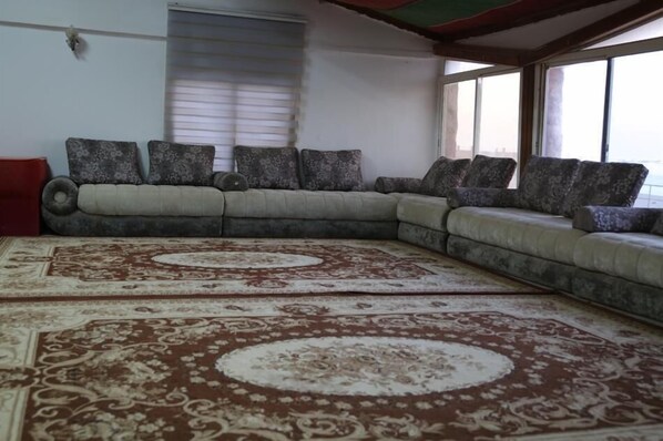 A living room with a large sectional sofa, patterned cushions, and a large decorative rug.