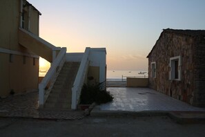 A coastal building with a staircase leading to a balcony overlooking the sea.