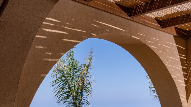 Un área de comedor al aire libre con vista al océano, que incluye una mesa, sillas y una pérgola.