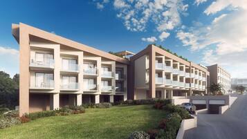 A modern hotel with multiple balconies, a well-maintained lawn, and a parking area.