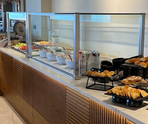 Zona de bufé con diversas opciones de comida y una barra de madera.