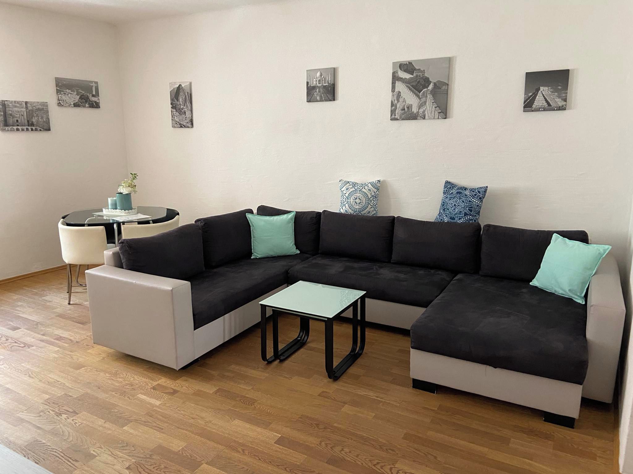 A modern living room with a sectional sofa, a small coffee table, and a round table with chairs.
