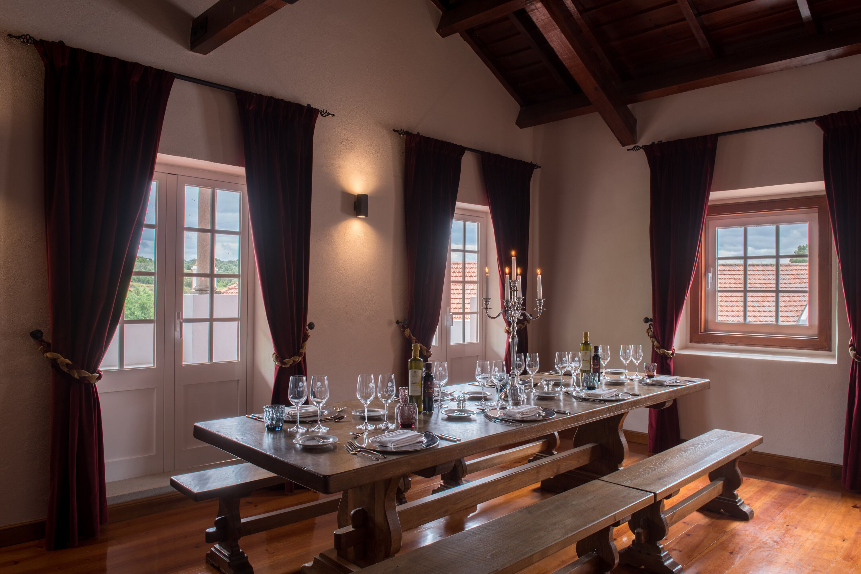 Mesa de comedor para seis personas, con velas, copas de vino y botellas.