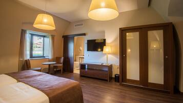 Una habitación de hotel con cama, escritorio, silla, televisión y armario.