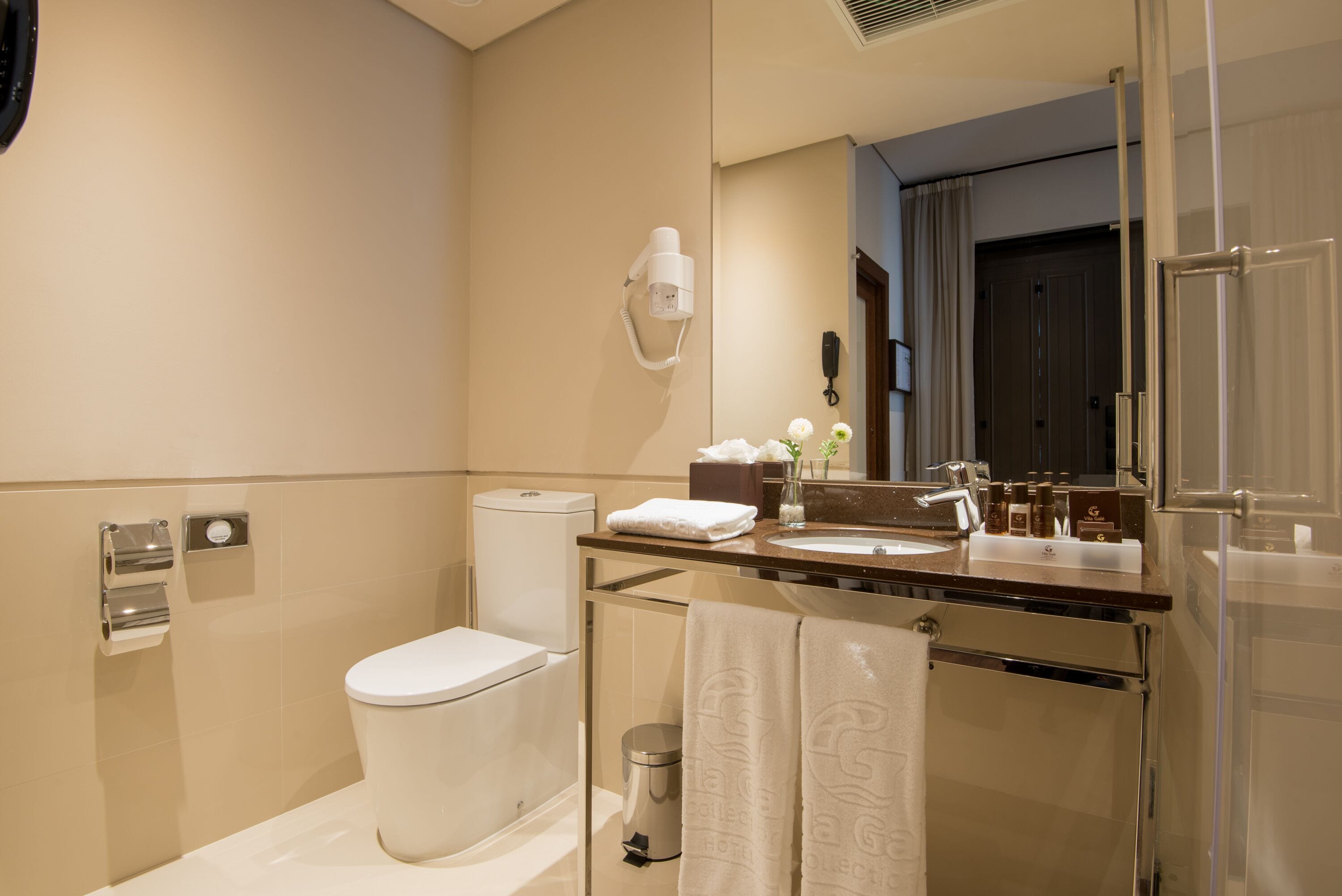 Un baño moderno con inodoro, lavamanos y espejo.