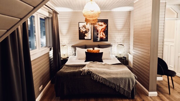 A bedroom with a bed, bedside tables, a chandelier, and artwork on the wall. - Heart of Reykjavik (Reykjavik)