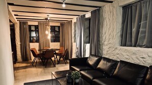 A modern living room with a leather sofa, a dining table with chairs, and a chandelier. - Heart of Reykjavik (Reykjavik)