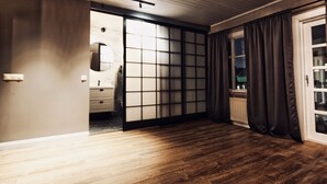 A room with a sliding shoji screen door, a wooden floor, a small sink, and a window with curtains. - Heart of Reykjavik (Reykjavik)