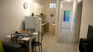 Una cucina compatta con zona pranzo, un piccolo frigorifero, un lavello e un forno a microonde.