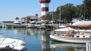 Uma marina com vários barcos atracados, um farol e um edifício com telhado vermelho.