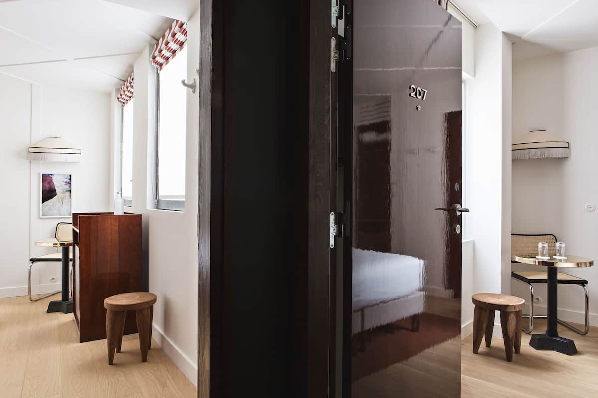 Ein Hotelzimmer mit einem Bett, zwei Hocker, einem kleinen Tisch und einem Sessel.