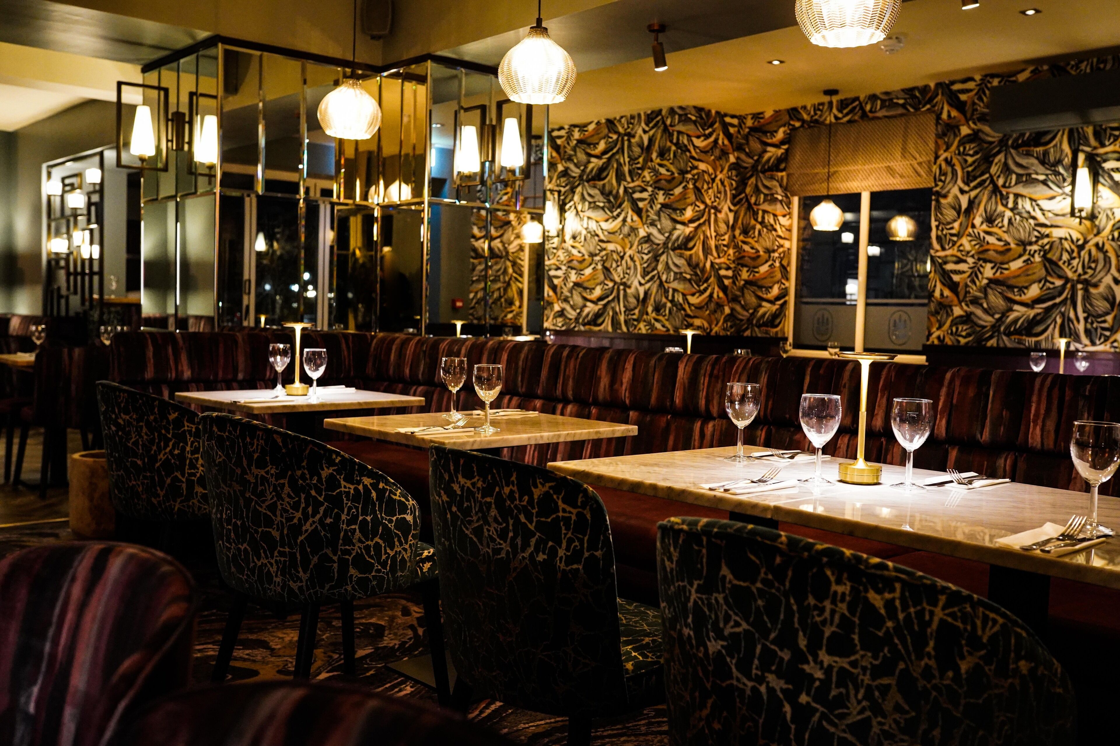 Un restaurante con cabinas y mesas, cada una con una copa de vino.