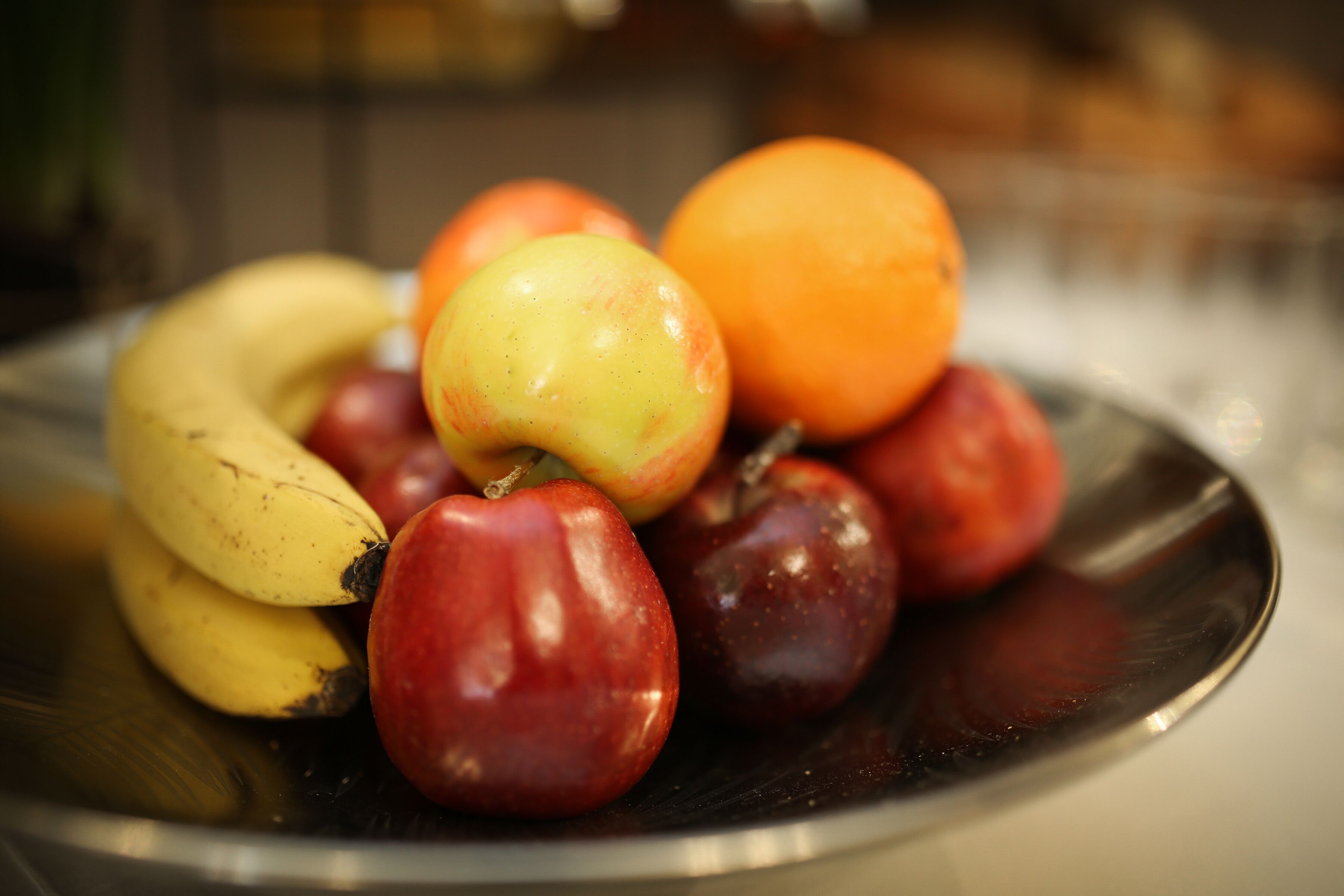 Un plato con varias frutas, entre ellas plátanos, manzanas y una naranja.