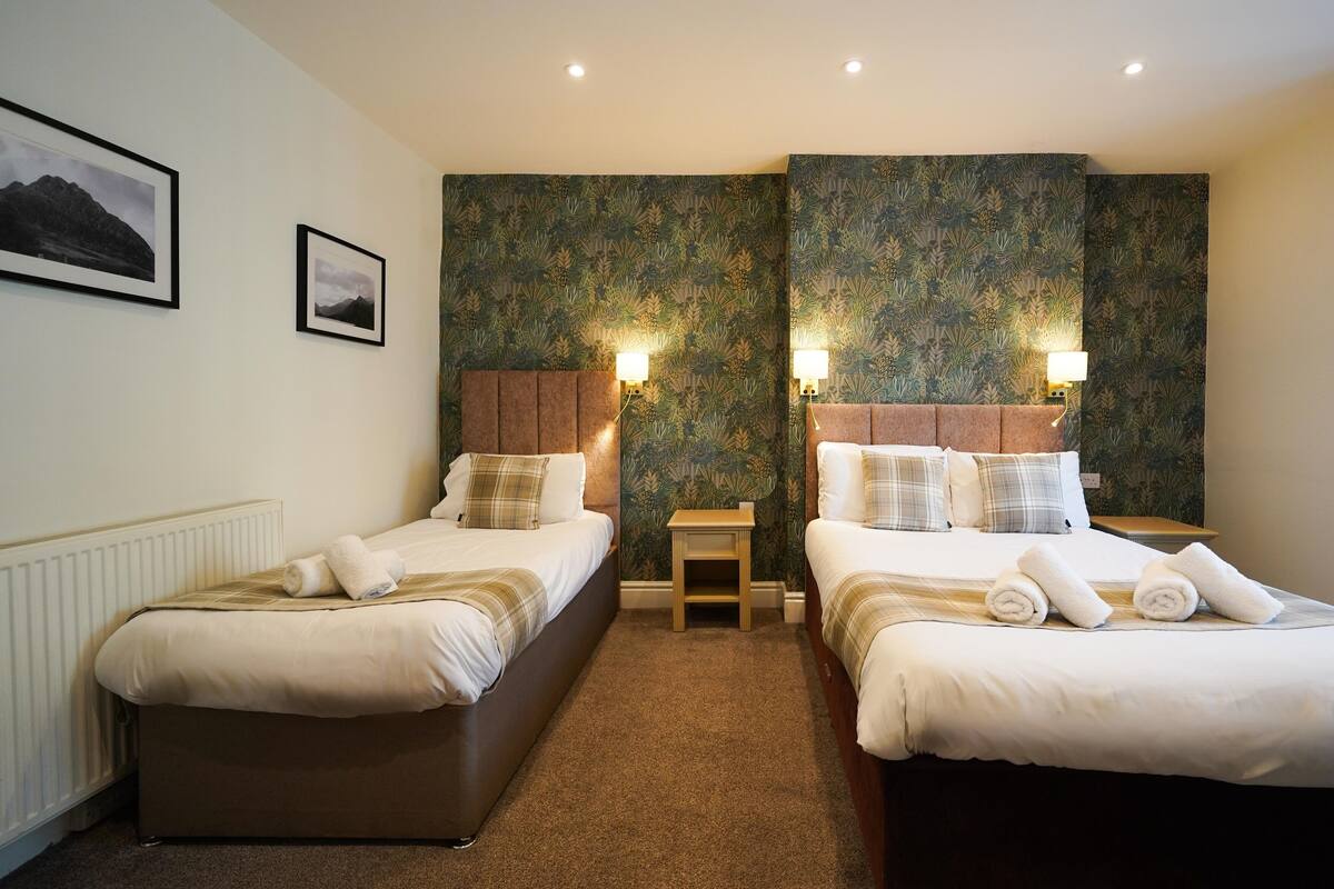 Hotellihuone, jossa on kaksi sänkyä, pieni pöytä ja patteri.
