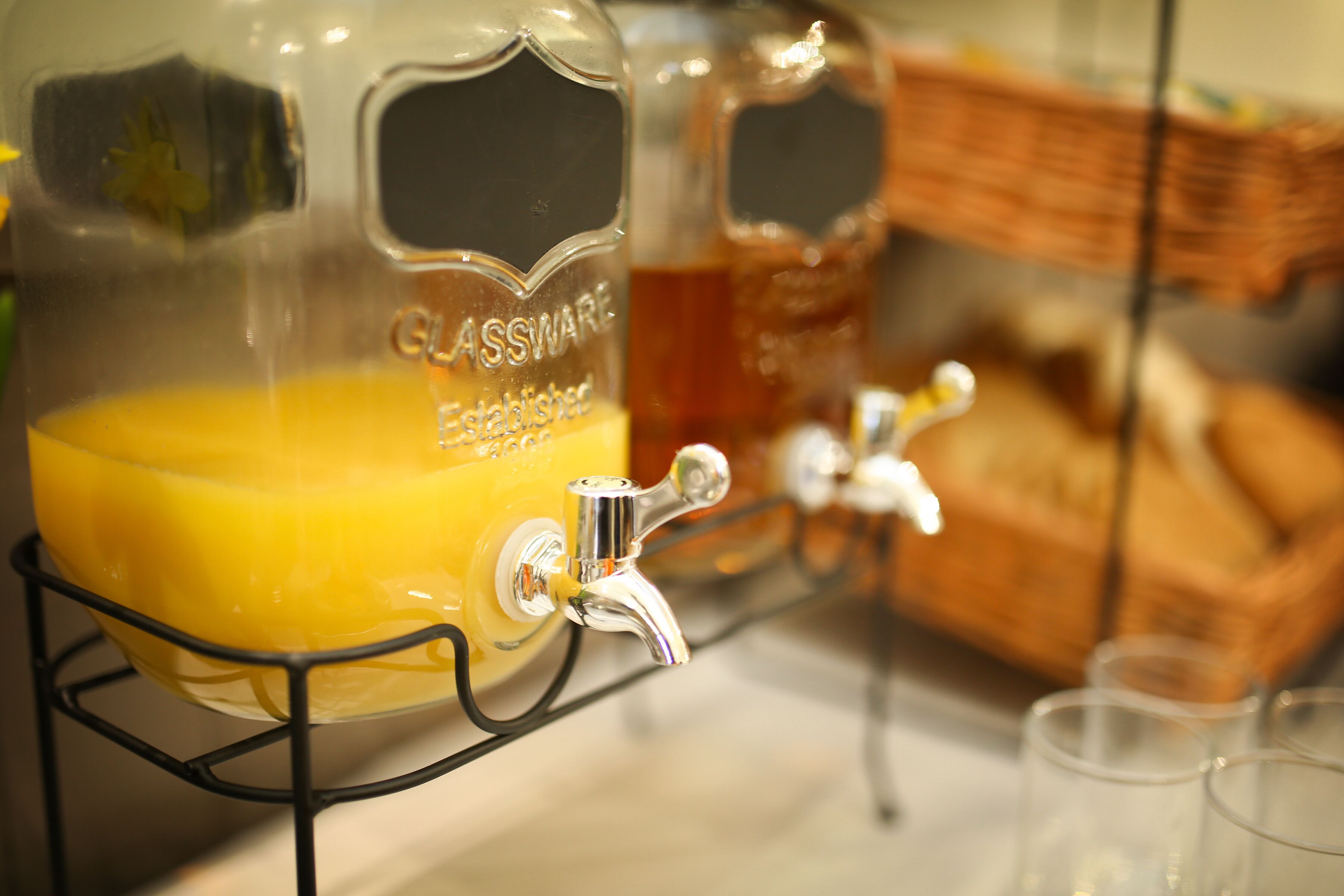 Un dispensador de begudes amb un recipient de vidre que porta l'etiqueta "GLASSWARE Established 1996" i un robinet.