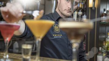 A bartender at a bar with a dark shirt featuring a logo and text.