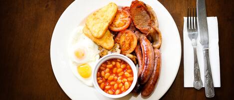 A plate of breakfast food including eggs, sausages, tomatoes, and beans.