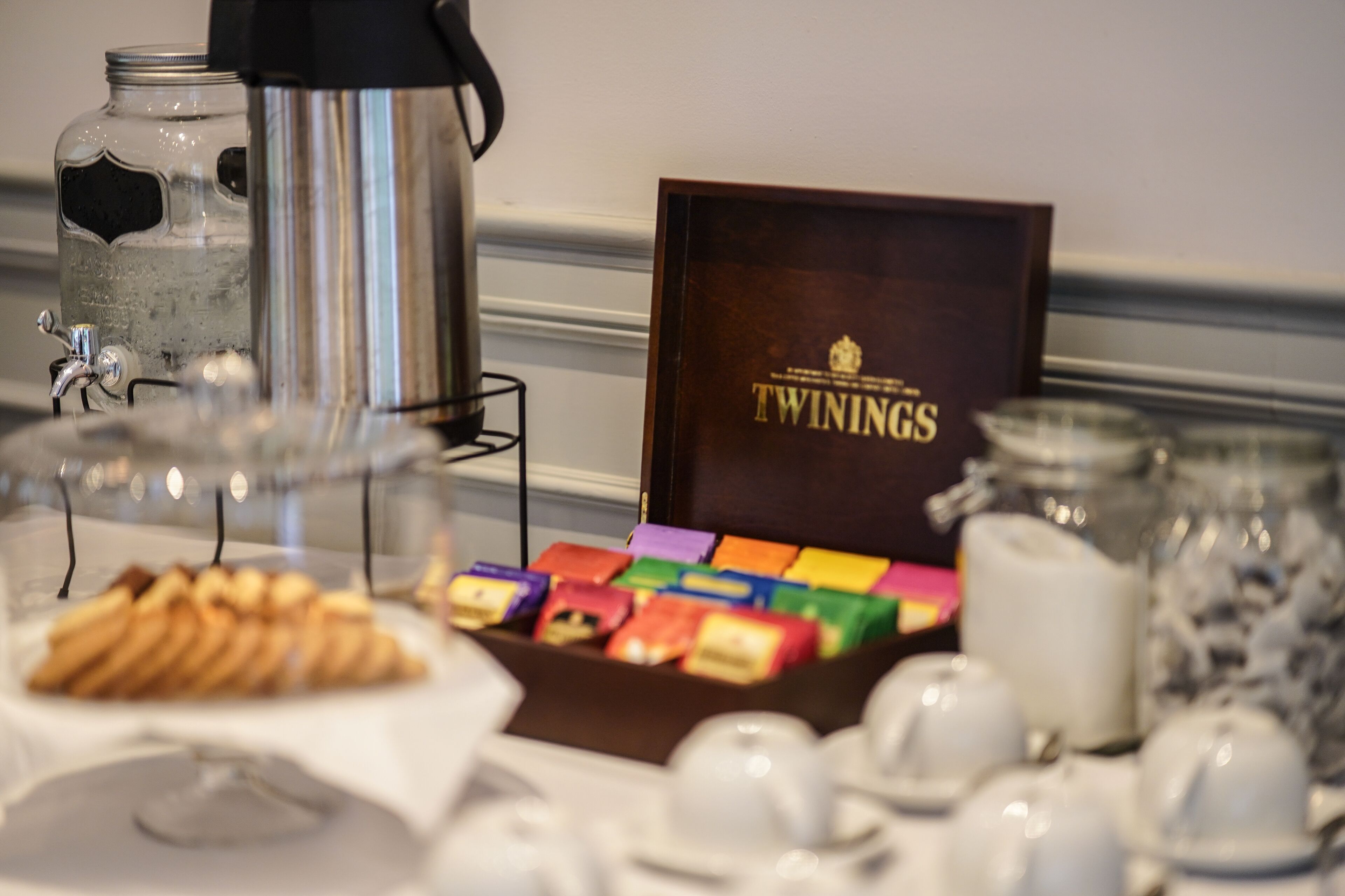 Disposição de buffet de café da manhã com uma cafeteira, uma caixa de chá Twinings e diversos tipos de comida.
