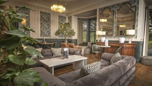 Uma sala de estar moderna com um sofá seccional, uma mesa de centro e um espaço de jantar com mesa e cadeiras. Há um espelho grande e uma planta no canto.