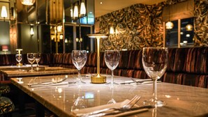 Um restaurante com mesas de mármore, cabines acolchoadas e iluminação ambiente.