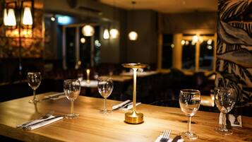 A dining table with a gold base, surrounded by empty wine glasses and cutlery, in a dimly lit restaurant setting.