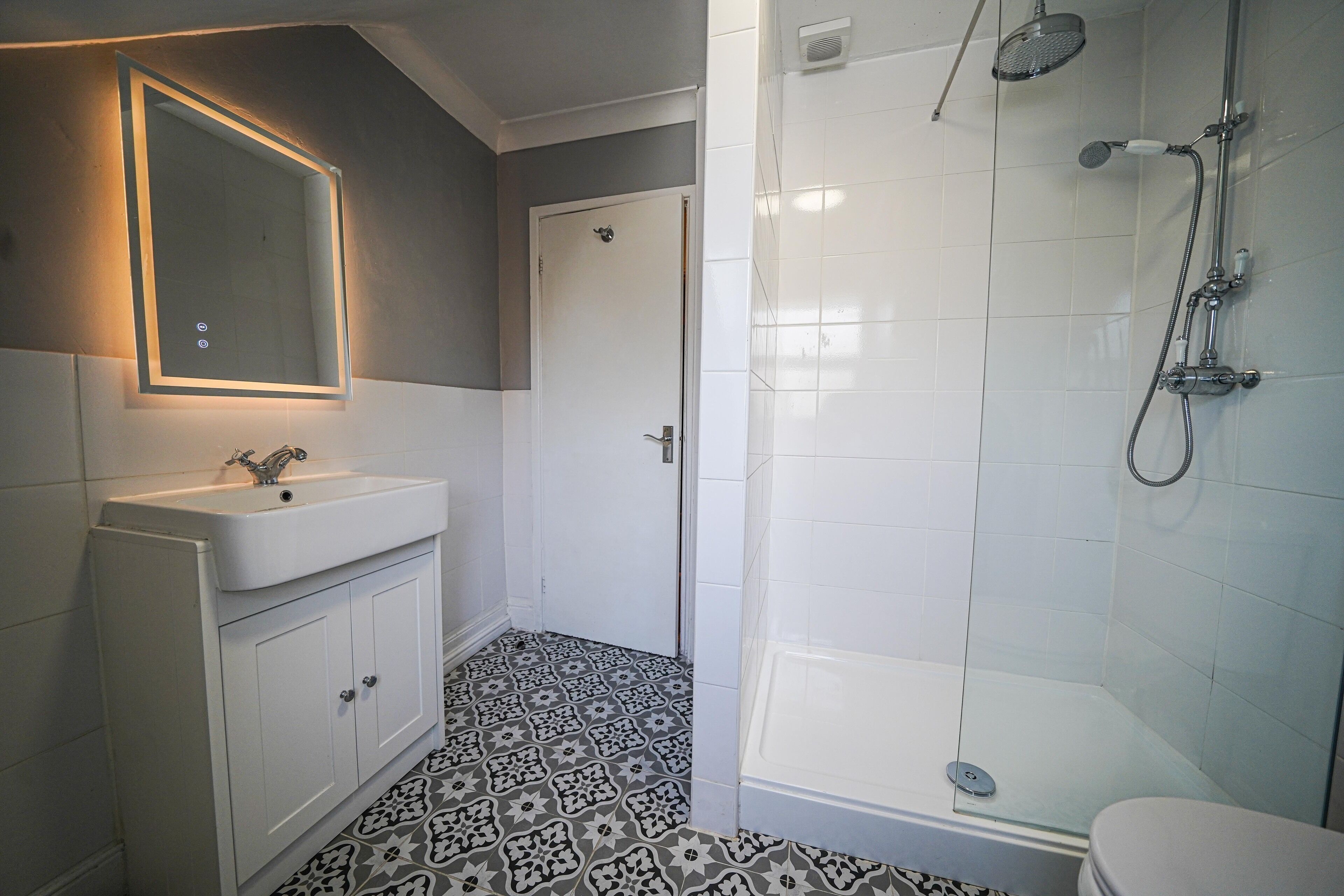 Ein Badezimmer mit Waschbecken, Spiegel und Dusche.