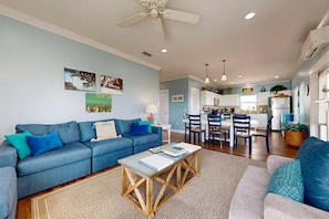 A living room with a blue sofa, a coffee table, and a dining area with chairs and a table.