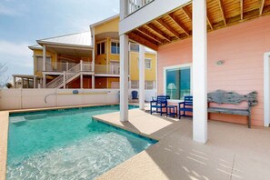 A two-story house with a swimming pool, outdoor seating, and a covered patio area.