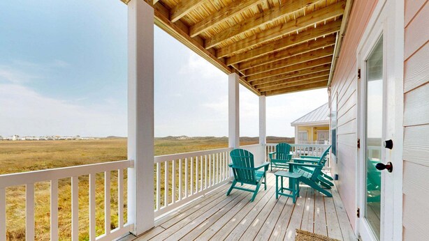 A covered porch with a wooden ceiling, white railings, and a view of the landscape. - Views of Ocean, Boardwalk to Beach and Golf Cart Included, Private Heated Pool, Pet Friendly (Port Aransas)