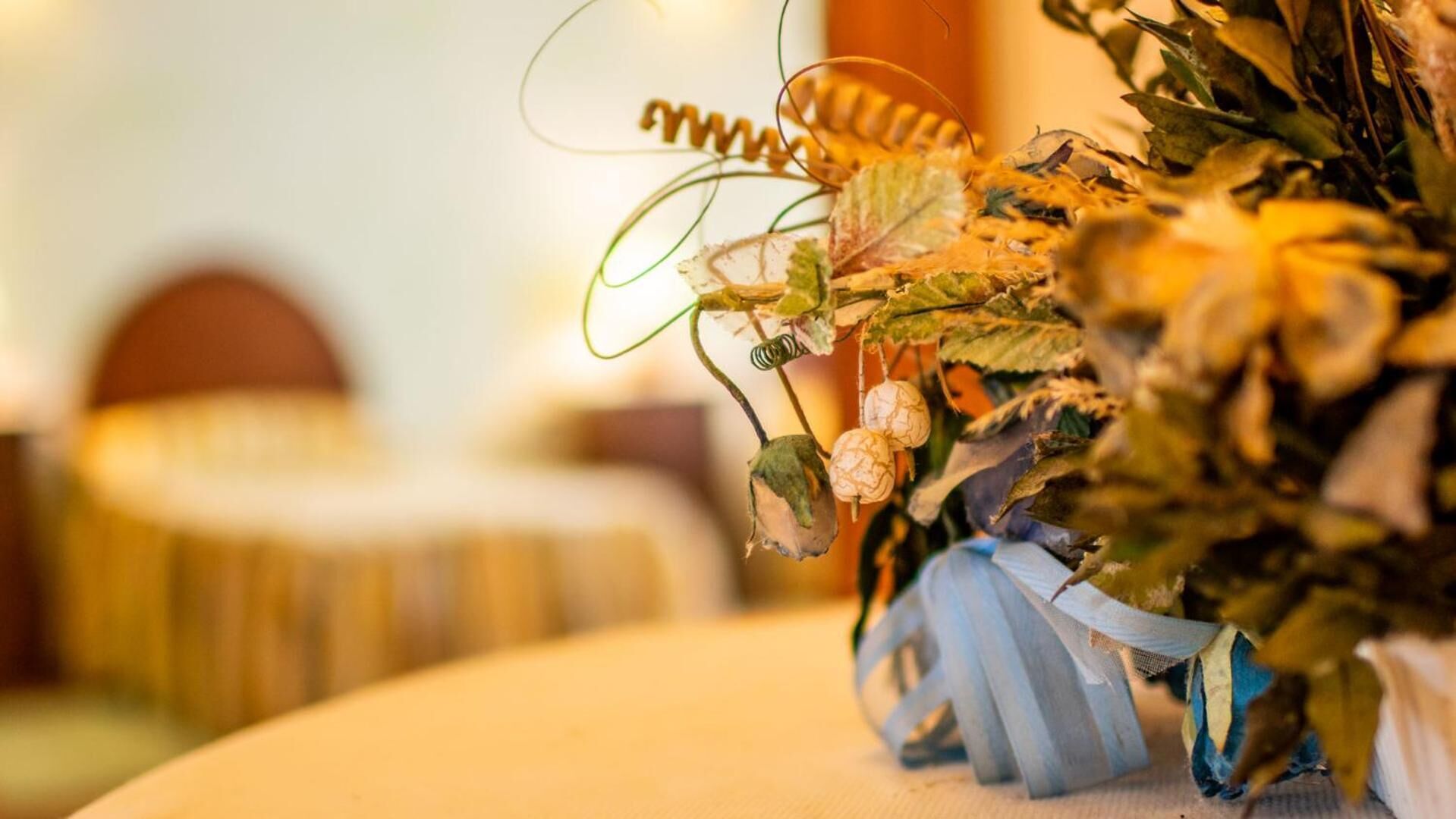 A close-up of a decorative arrangement with a ribbon and dried flowers.
