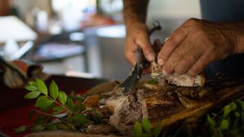 A person carving meat on a cutting board with a knife.