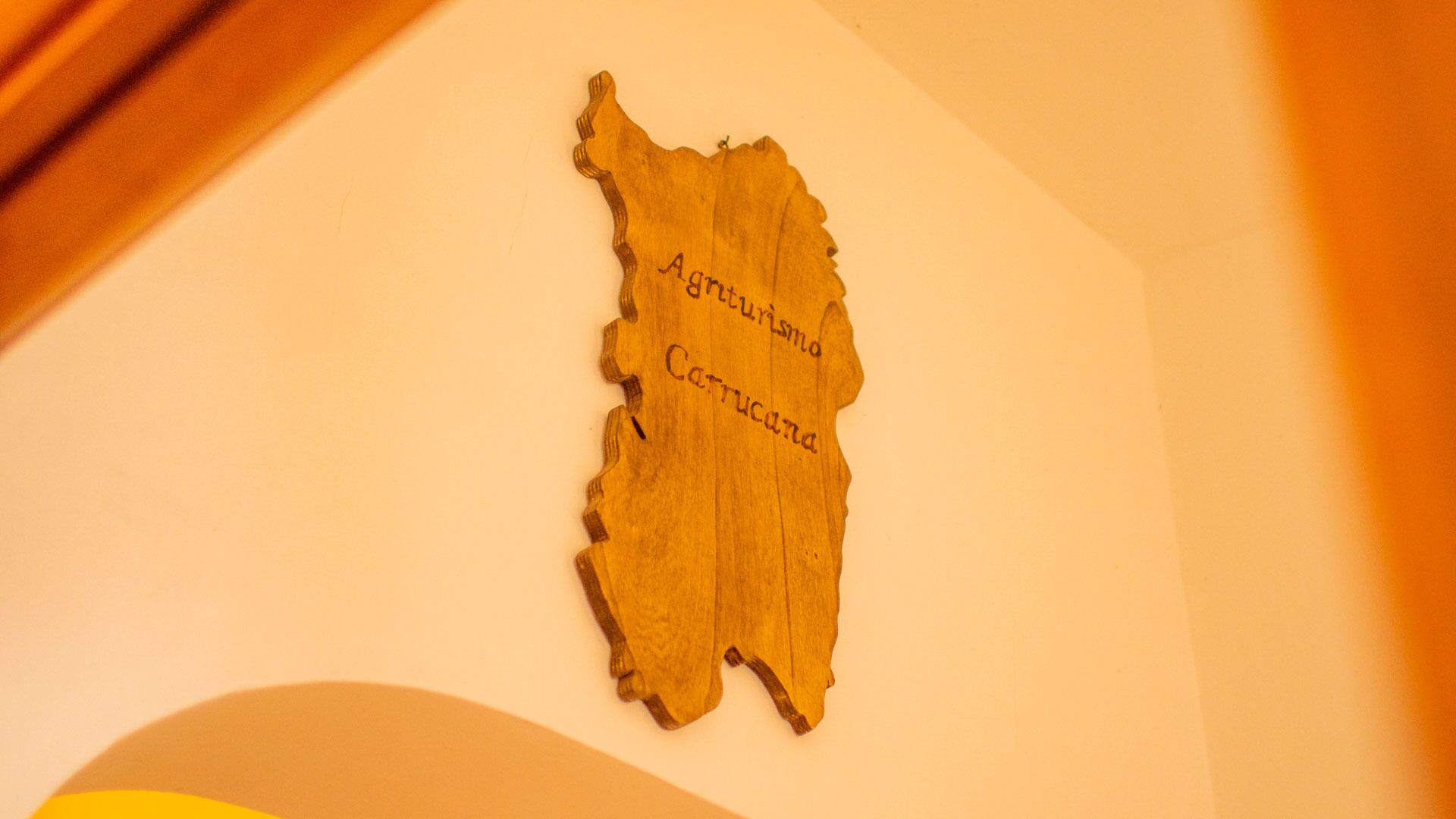 A wooden plaque with the text "Agriturismo Catucana" on a wall.