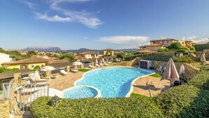 A swimming pool with a view of surrounding buildings and hills. - Belvedere Suite G - flat with pool in Pittulongu (Olbia)