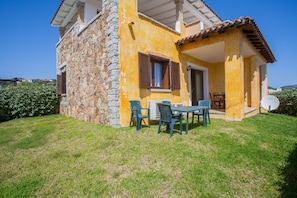 A house with a stone facade, a tiled roof, and a small patio with outdoor furniture. - Belvedere Suite G - flat with pool in Pittulongu (Olbia)