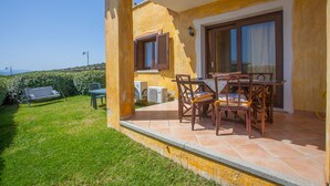 A patio with a table and chairs, a swing, and a view of the countryside. - Belvedere Suite G - flat with pool in Pittulongu (Olbia)