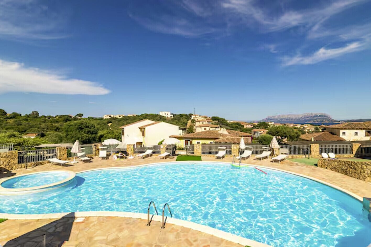 A swimming pool with lounge chairs and a view of houses in the background.
