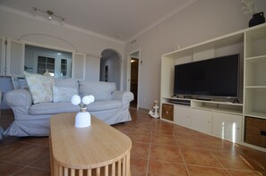Ein Wohnzimmer mit einer Couch, einem Fernseher und einem Holztisch.