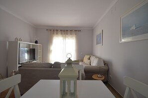 A living room with a TV, sofa, table, and a lamp.