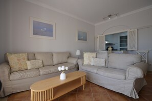 Una sala de estar con dos sofás, una mesa de centro de madera y dos cuadros enmarcados en la pared.