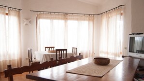 Un comedor con una gran mesa de madera, sillas y un televisor.