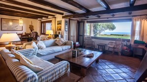 A cozy living room with a sofa, coffee table, and chairs, featuring a view of the outdoors.