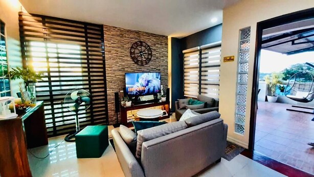 A modern living room with a flat-screen TV, a sofa, a coffee table, and a decorative wall clock. - Overlooking (Antipolo)