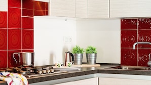 A modern kitchen with a gas stove, stainless steel pots, and potted plants on the counter.