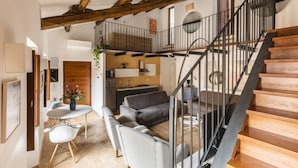 A modern interior with a wooden staircase, a dining area with a white table and chairs, and a gray sofa. - Margana Palace by ROMAC (Rome)
