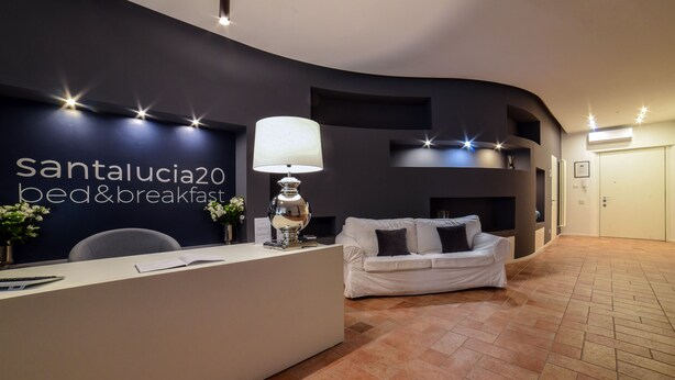 Un área de recepción con una pared curva, un mostrador blanco, un sofá blanco y una lámpara.