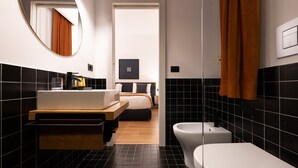 Un baño moderno con suelo de mosaicos blanco y negro, tocador de madera, inodoro blanco y bidé.