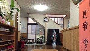 A traditional Japanese interior with a wooden floor, a clock, a vase, and a shoe rack. - Minshuku Unzen (Unzen)