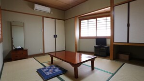 A traditional Japanese room with tatami flooring, a low wooden table, sliding doors, and a television. - Minshuku Unzen (Unzen)
