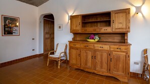 Una stanza con un armadio in legno, sedie in vimini e un pavimento piastrellato.