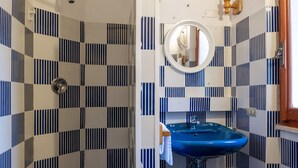 Un bagno con pavimento a scacchi blu e bianco, un lavandino blu e una zona doccia.